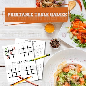 Könnte beinhalten: Druckbare Tischspiele, darunter Tic Tac Toe und Punkte und Kästchen, werden mit farbigen Buntstiften dargestellt. Das Bild zeigt einen weißen Holztisch mit verschiedenen Gerichten, Gewürzen und dem Text "PRINTABLE TABLE GAMES".