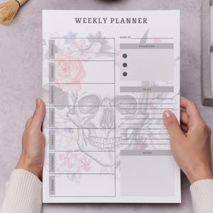 May include: A weekly planner with a skull and floral design. The planner includes sections for each day of the week, priorities, to-do lists, and notes. The text "WEEKLY PLANNER" is at the top.