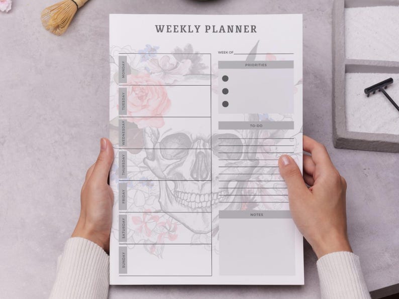 May include: A weekly planner with a skull and floral design. The planner includes sections for each day of the week, priorities, to-do lists, and notes. The text "WEEKLY PLANNER" is at the top.