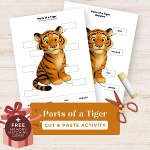 May include: Educational worksheet titled "Parts of a Tiger" with a cartoon tiger illustration. The worksheet includes labels for cutting and matching, along with an answer sheet. A glue stick and scissors are also visible. The image also includes a gift box with the text "FREE MEMORY MATCHING GAME!"