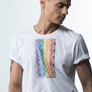 May include: A white t-shirt featuring a rainbow patterned design on the front. The pattern is made up of colourful geometric shapes.