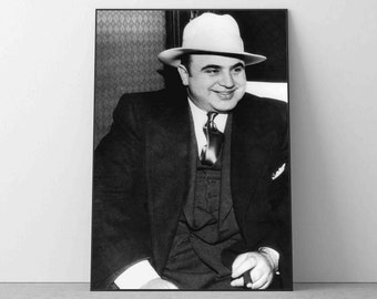 Op de afbeelding: Zwart-wit portret van een man met een witte fedora en een pak. Hij glimlacht en kijkt naar de camera.