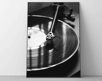 Puede incluir: Una fotografía en blanco y negro de un tocadiscos con un disco de vinilo en el plato giratorio. La aguja está en el surco del disco y el brazo de lectura está extendido.