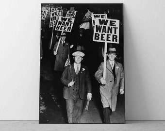 May include: Black and white photo of a group of people marching down a street, holding signs that read "We Want Beer".