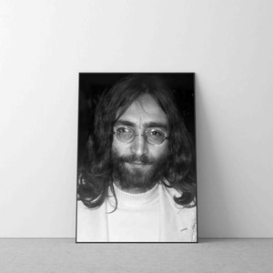 May include: Black and white portrait photograph of a man with long hair and a beard wearing round glasses. He is looking directly at the camera.