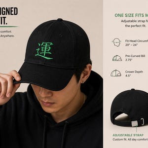 May include: Black baseball cap with a green embroidered Chinese character. The cap has an adjustable strap and a pre-curved bill. Text on the image reads "Designed to Fit" and "One Size Fits Most".
