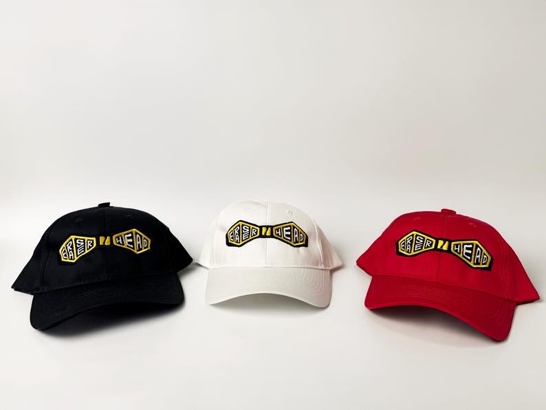 May include: Three baseball caps with a black, white, and red color scheme. Each cap features a yellow and black bow tie design with the text "ER SIR HEAD" embroidered on it.