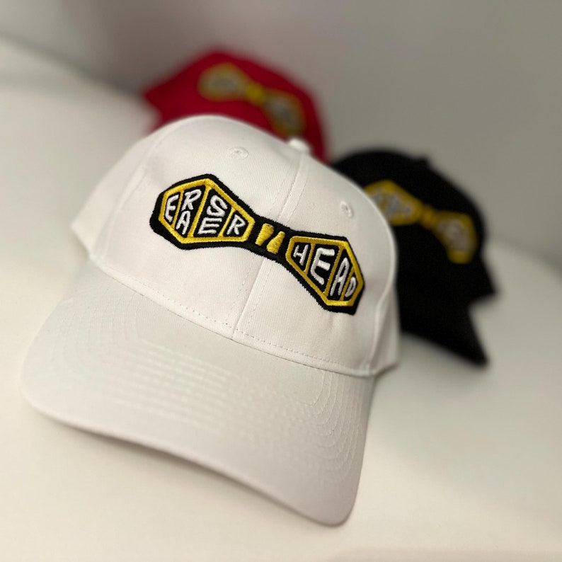 May include: White baseball cap with a black and gold embroidered patch that says "ERSR HEAD".