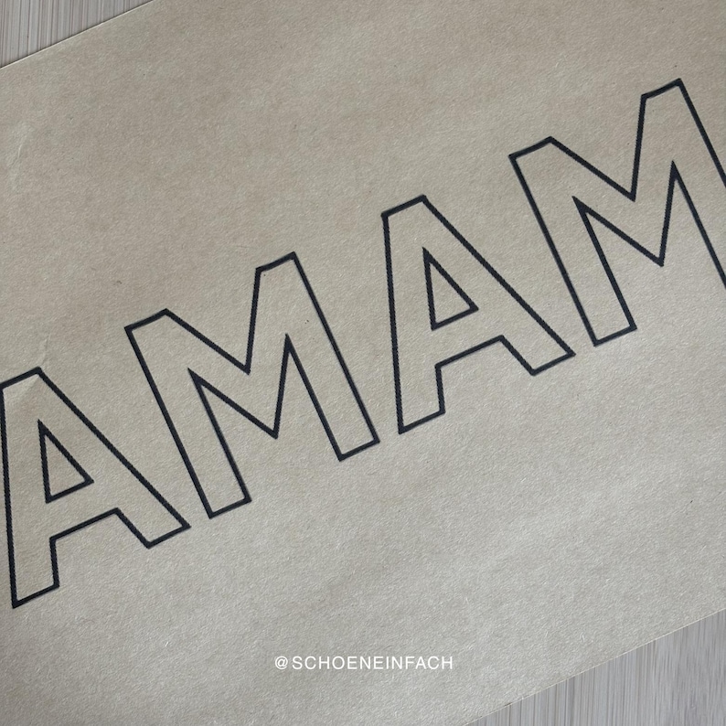Puede incluir: Primer plano de un papel beige con la palabra "AMAM" en letras negras y en negrita. La esquina inferior derecha del papel tiene el texto "@SCHOENEINFACH" en una fuente m&aacute;s peque&ntilde;a.