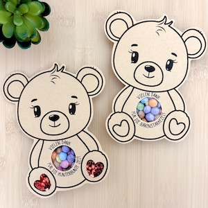 以下が含まれることがあります： 笑顔のクマの黒い線画が描かれた、クマの形をしたクラフト紙のカード2枚。各カードには小さな色とりどりのキャンディが入った円形の切り抜きがあり、「Vielen Dank für die kunterbunte Zeit」または「Bärenstarke Zeit」というテキストが印刷されています。