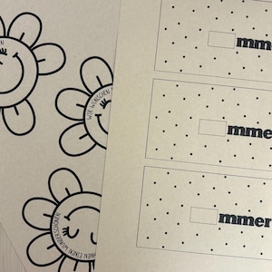 Pu&ograve; includere: Un foglio di carta beige con disegni a linee nere di fiori sorridenti con petali e il testo tedesco WIR W&Uuml;NSCHEN EINEN WUNDERSCH&Ouml;NEN, accanto a un secondo foglio con pois neri e rettangoli contenenti il testo mmer.
