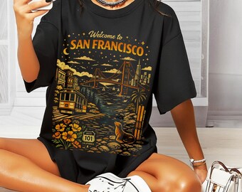 May include: Black t-shirt with a graphic design that says "Welcome to San Francisco." The design features the Golden Gate Bridge, a cable car, and a sea lion. The shirt also has the Route 101 sign.