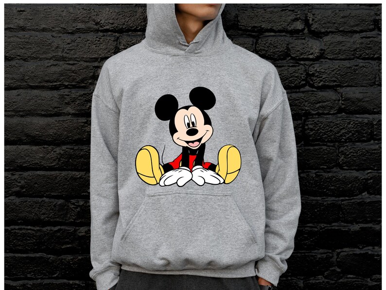 May include: A gray hooded sweatshirt featuring a large graphic of Mickey Mouse. The cartoon character is depicted in his classic pose, with black ears, a red shirt, white gloves, and yellow shoes. The sweatshirt has a front pocket and a drawstring hood.