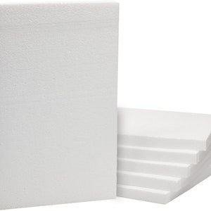 May include: A set of rectangular white foam boards with a textured, porous surface. One board stands vertically on its edge, while several identical boards are stacked horizontally behind it, creating a clean, uniform appearance for crafting.