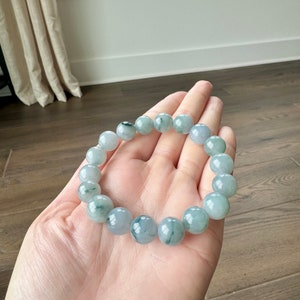 May include: A jade bracelet with green and white beads. The bracelet is made of natural jade and has a polished finish.