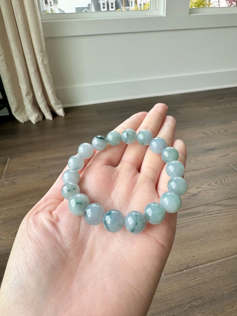 May include: A jade bracelet with green and white beads. The bracelet is made of natural jade and has a polished finish.