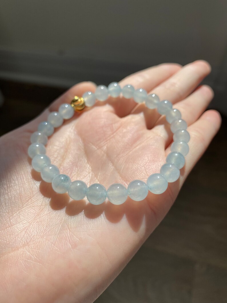 K&ouml;nnte beinhalten: Ein hellblaues Edelstein-Armband mit einem goldenen Verschluss. Das Armband besteht aus runden Perlen und ist etwa 18 cm lang.