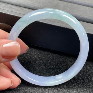 Op de afbeelding: Een lichtblauwe jade armband. De armband is glad en gepolijst, met een subtiele groene tint.