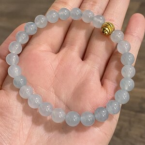 K&ouml;nnte beinhalten: Ein hellblaues Edelstein-Armband mit einem goldenen Perlenakzent. Das Armband besteht aus runden Perlen und ist etwa 18 cm lang.