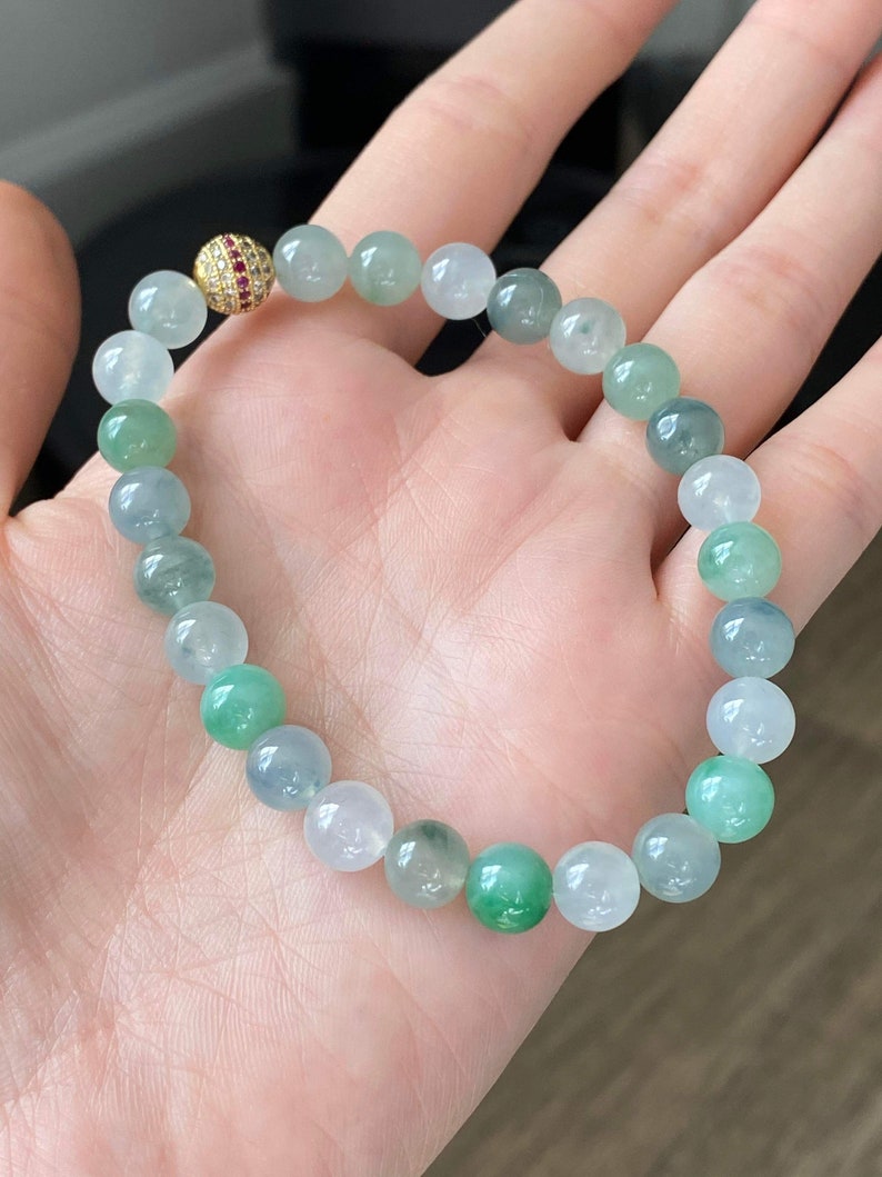 Pode incluir: Um bracelete de jade&iacute;ta com um fecho de ouro e rubi. O bracelete &eacute; feito de contas redondas em tons de verde e branco.