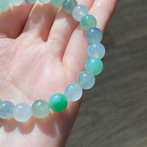 Pode incluir: Um bracelete de jade com contas verdes e brancas. As contas s&atilde;o redondas e lisas.