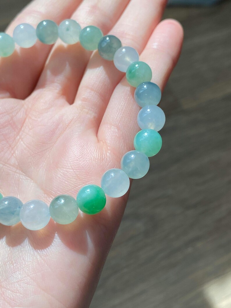 Pode incluir: Um bracelete de jade com contas verdes e brancas. As contas s&atilde;o redondas e lisas.