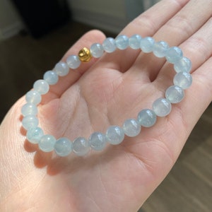 K&ouml;nnte beinhalten: Ein hellblaues Edelstein-Armband mit einem goldenen Verschluss. Das Armband besteht aus runden Perlen und ist etwa 18 cm lang.