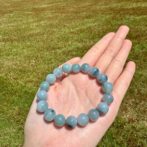 May include: A jade bracelet with green and white beads. The bracelet is made of natural jade and has a smooth, polished finish.