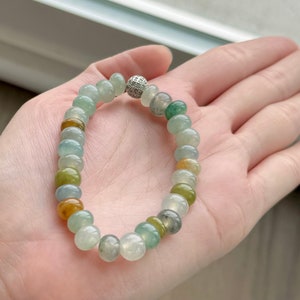 May include: A jadeite bracelet with a silver clasp and a variety of green, yellow, and white beads.