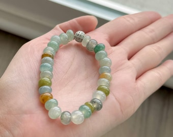 Pode incluir: Um bracelete de jadeíta com fecho de prata e uma variedade de contas verdes, amarelas e brancas.