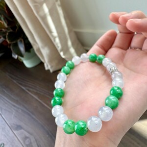 May include: A jade bracelet with white and green beads. The bracelet is made of natural jade and has a silver clasp.