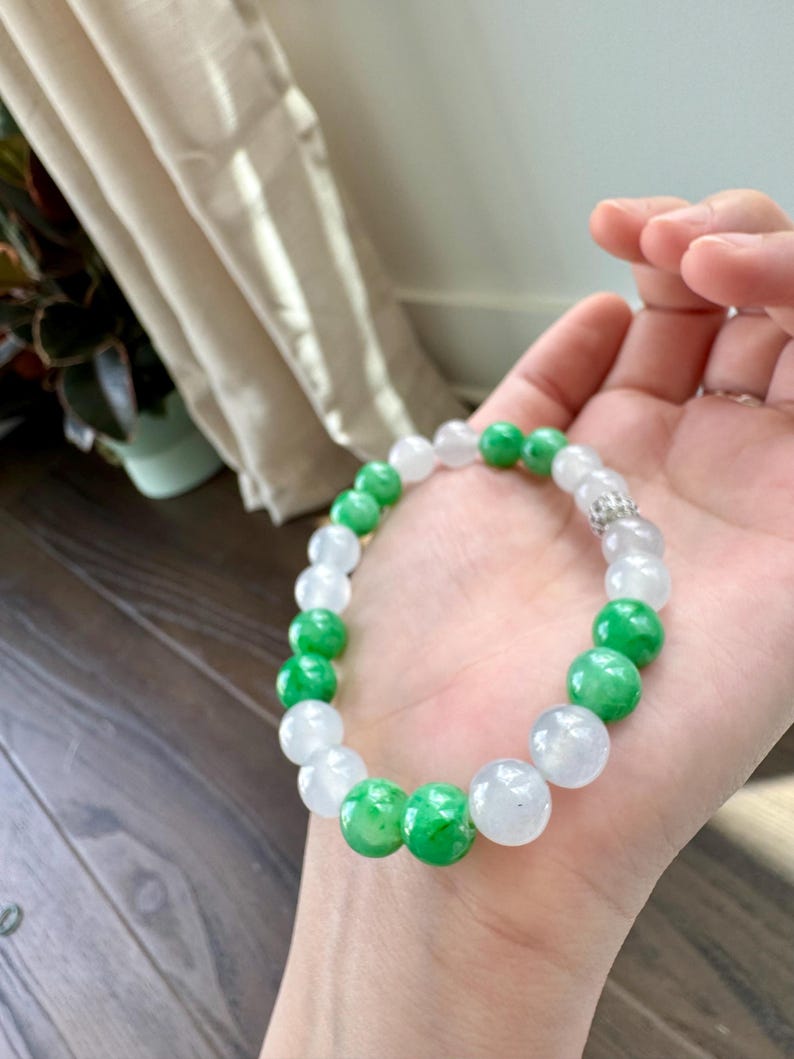 May include: A jade bracelet with white and green beads. The bracelet is made of natural jade and has a silver clasp.