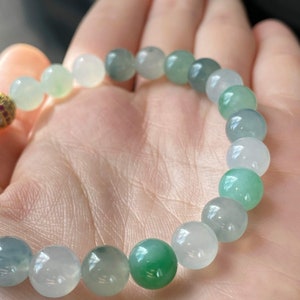 Pode incluir: Um bracelete de jade com contas redondas em tons de verde e branco.