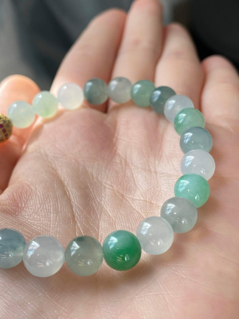 Pode incluir: Um bracelete de jade com contas redondas em tons de verde e branco.