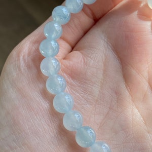 May include: A light blue gemstone bracelet with round beads.