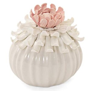 May include: White ceramic vase with a ruffled, flower-shaped lid. The lid is decorated with a pink flower.