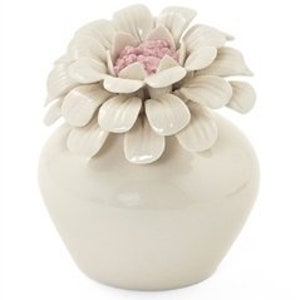 Könnte beinhalten: Eine weiße Keramikvase mit einer großen, weißen Keramikblume darauf. Die Blume hat rosa Blütenblätter in der Mitte.