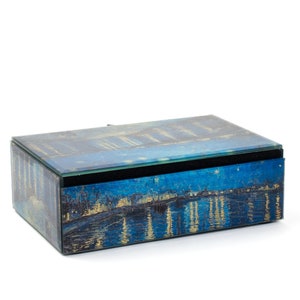 Puede incluir: Una caja de joyería de vidrio azul con una pintura de una escena de noche estrellada en la tapa y los lados. La caja tiene un interior de terciopelo negro.