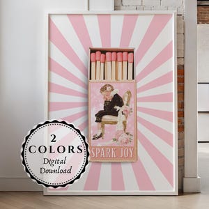 以下が含まれることがあります： ピンクと白のストライプの背景に、大きなマッチ箱のデザインが施された額入りのアートワーク。マッチ箱には、椅子に座っている人のヴィンテージイラストと「SPARK JOY」の文字が描かれています。円形のラベルには「2 COLORS Digital Download」と書かれています。