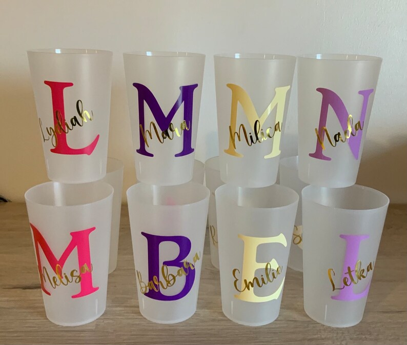 May include: Nine clear plastic cups with gold lettering and a different name on each cup. The names are: Lylah, Mara, Milena, Nadia, Melissa, Barbara, Emilie, Letka.