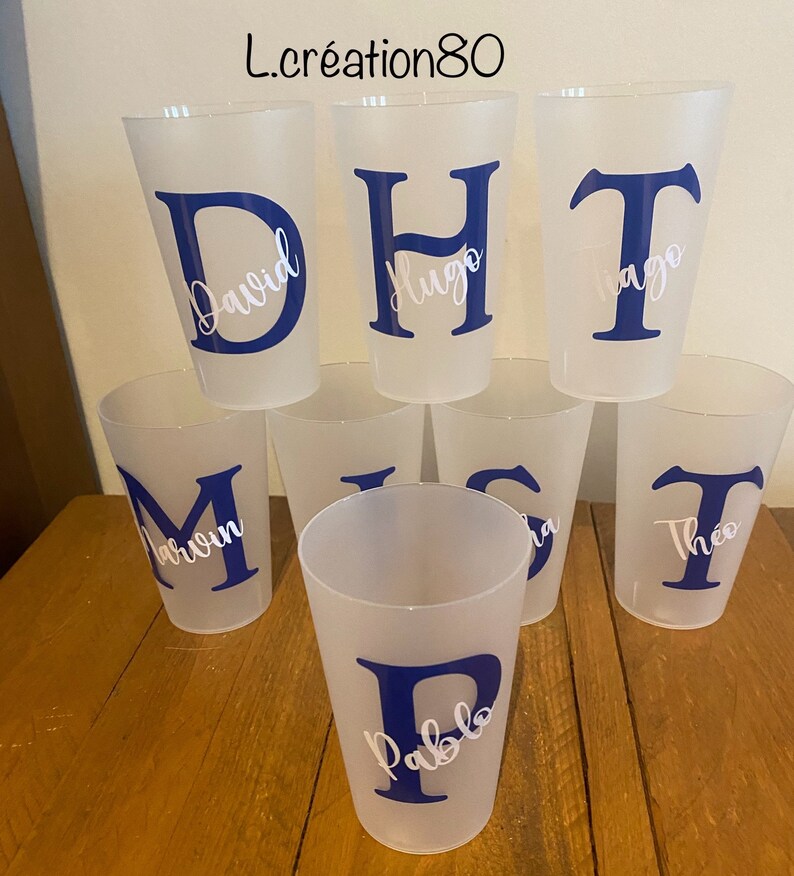 May include: Seven clear plastic cups with blue letters and white names on them. The names are David, Hugo, Tiago, Marvin, Pablo, Lisa, and Theo.