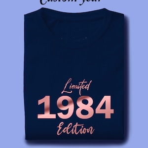 May include: A navy blue t-shirt with a rose gold design that says "Limited 1984 Edition".