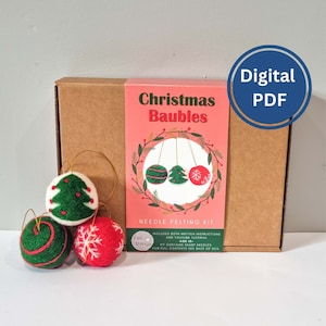 Peut inclure: Une boîte en carton marron avec une étiquette rose et verte qui dit "Christmas Baubles Needle Felting Kit". L'étiquette a une image de trois boules de Noël en feutre suspendues à une ficelle. La boîte contient trois boules de Noël en feutre : un sapin de Noël vert, une boule rouge avec un flocon de neige et une boule verte avec un tourbillon rouge. La boîte est étiquetée "Felt things" et comprend à la fois des instructions écrites et un tutoriel YouTube.