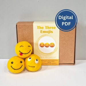 May include: A brown box with a yellow label that says "The Three Emojis" and a picture of three yellow smiley faces. The box is a needle felting kit that includes written instructions and a YouTube tutorial. The kit contains sharp needles.  The box is sitting on a white surface with three yellow felt emoji balls in front of it.