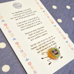 May include: A colourful felt bug buddy with a smiling face and rainbow-coloured yarn. The bug is holding a card with a poem about being brave and a reminder to take deep breaths. The card is decorated with a border of small, colourful felt shapes.
