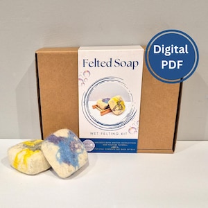 May include: A brown cardboard box with a white label reading "Felted Soap" and "Wet Felting Kit." The kit includes instructions and a YouTube tutorial. Two felted soaps with yellow and blue accents are in front of the box. A blue circle with "Digital PDF" is on the right.