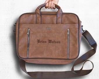 Puede incluir: Un maletín de cuero marrón con una correa para el hombro. El maletín tiene un bolsillo con cremallera en la parte delantera y el nombre "Brian Watson" está grabado en la parte delantera.