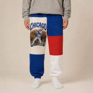 May include: Color-blocked sweatpants featuring a cream panel on the left leg with a graphic of a skeleton baseball player and two bears, with the word CHICAGO printed above. The right leg has horizontal blocks of blue, red, and white fabric.