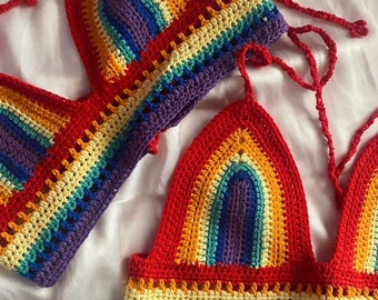 May include: Two rainbow crochet tops with a halter style and tie closures. The tops are made with a variety of colors, including red, orange, yellow, green, blue, indigo, and violet.