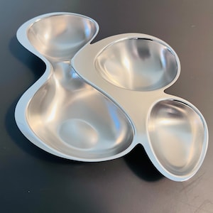 Puede incluir: Un plato de servir plateado con cuatro compartimentos separados, cada uno con una forma redondeada en forma de cuenco.